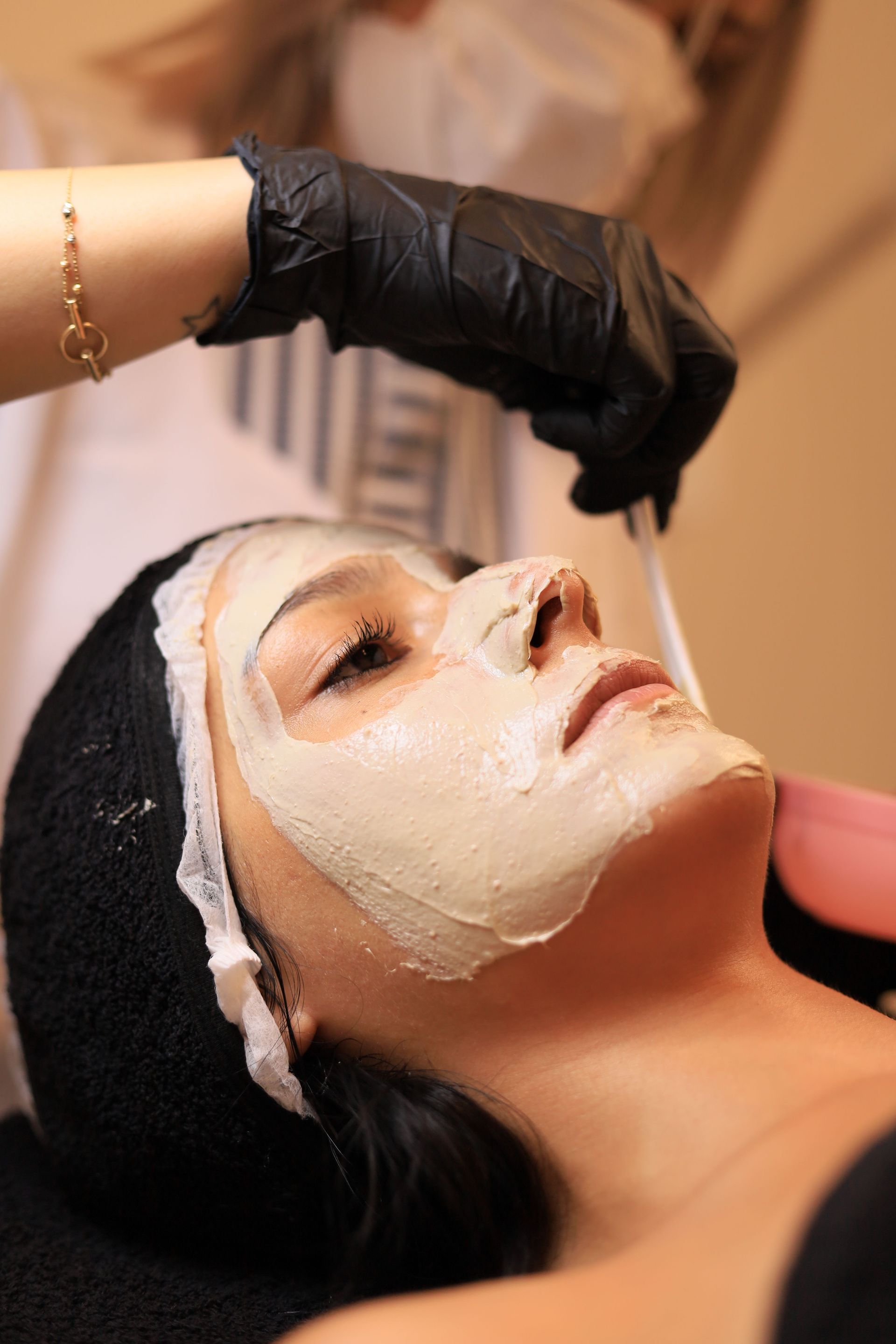 Woman receiving a soothing facial mask application at a spa, promoting relaxation and skincare.
