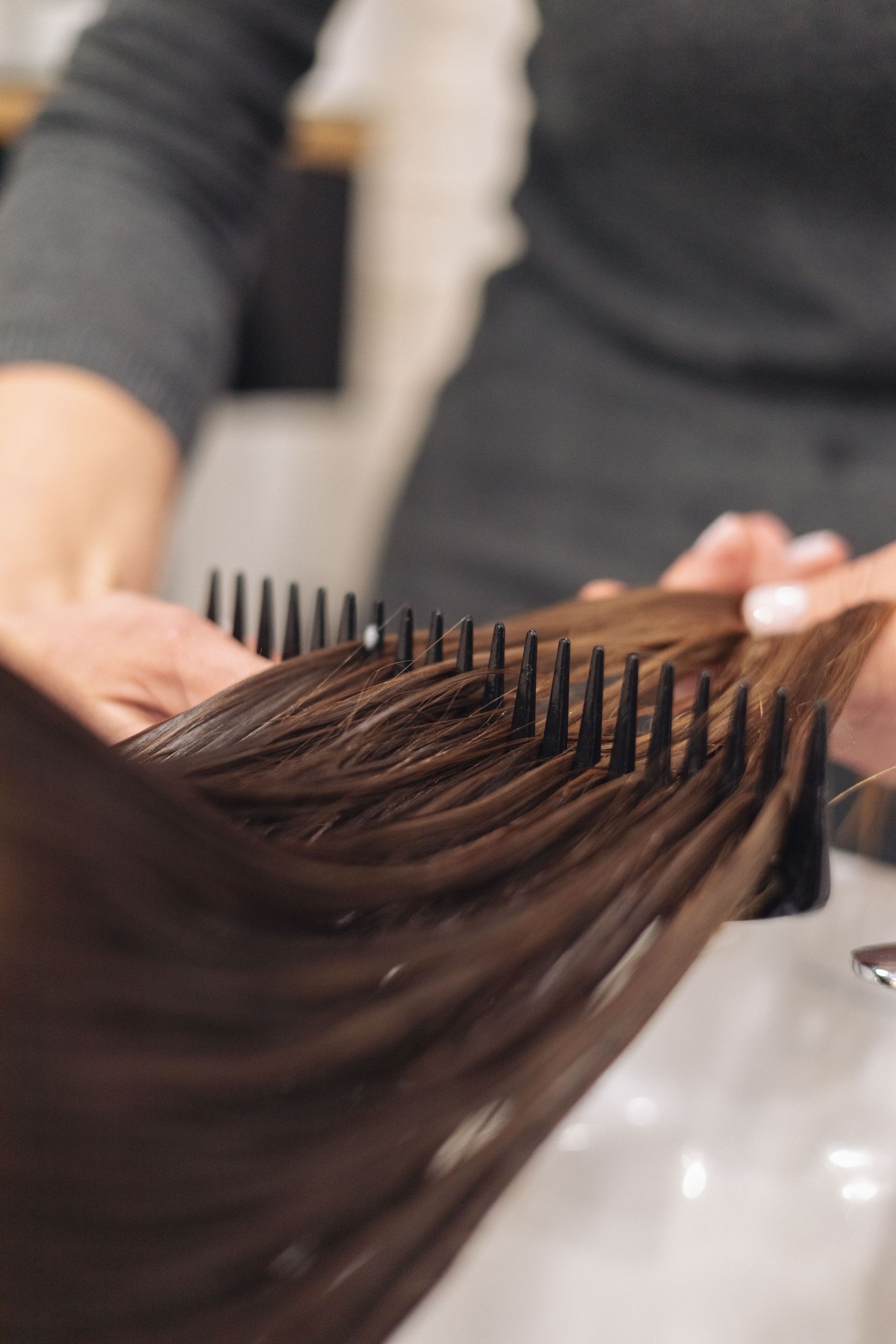 A hairdresser skillfully combs wet hair, focusing on smooth styling in a salon setting.
